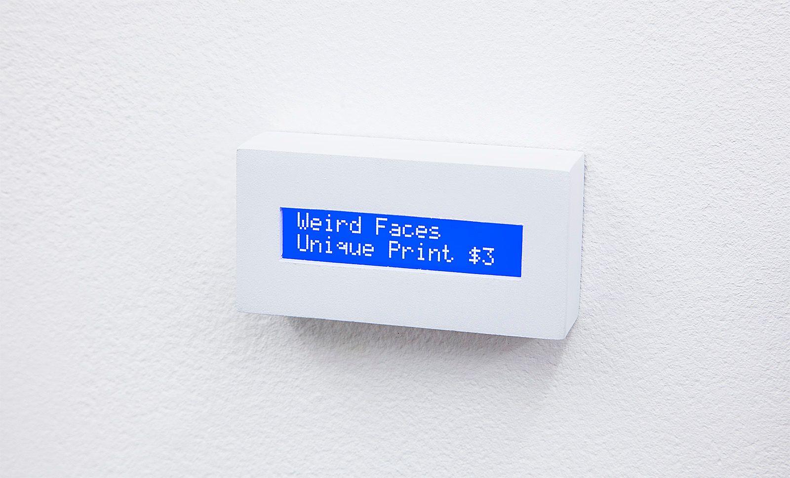 There is a small rectangular screen-like object jutting out from the white wall with the small text "Weird Faces Unique Print $3".