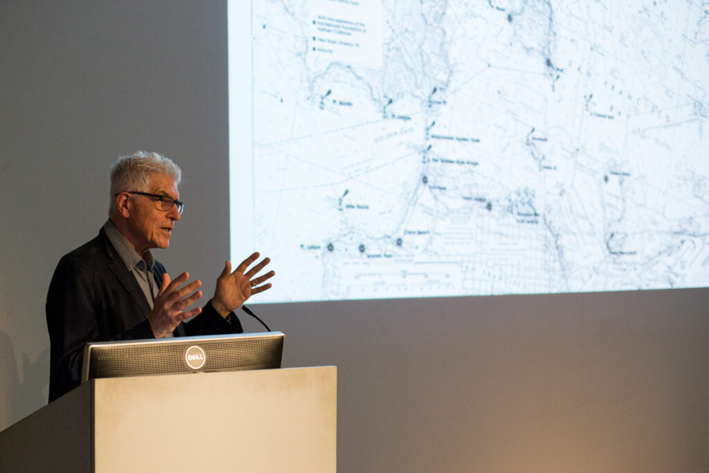 Bill Fontana gesturing with his hands while giving his lecture.