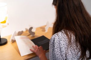 Person sitting at a table reading a book.