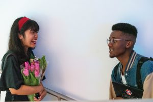 Person holding flowers on left next to Person holding a laptop on right.