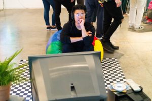 Person sitting on a beanbag looking at a television.