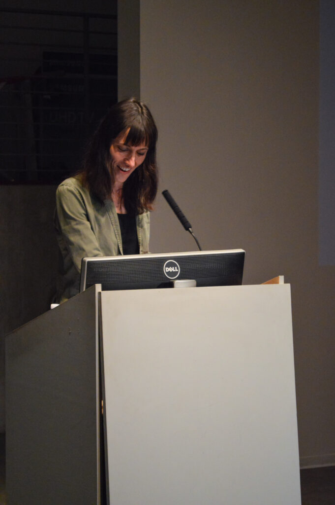 Astra taylor is speaking at a pedestal.
