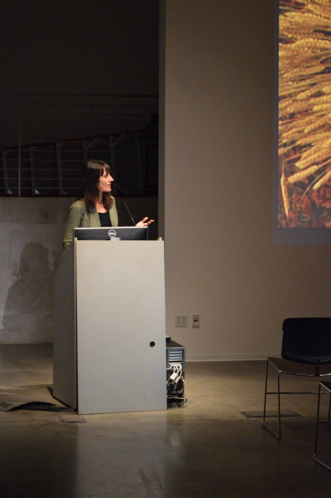 Astra taylor is speaking at a pedestal.