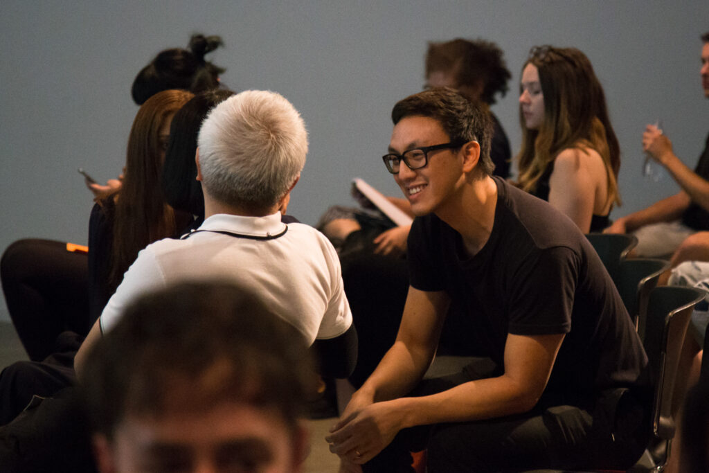 Ian Cheng smiling and talking to an audience member.