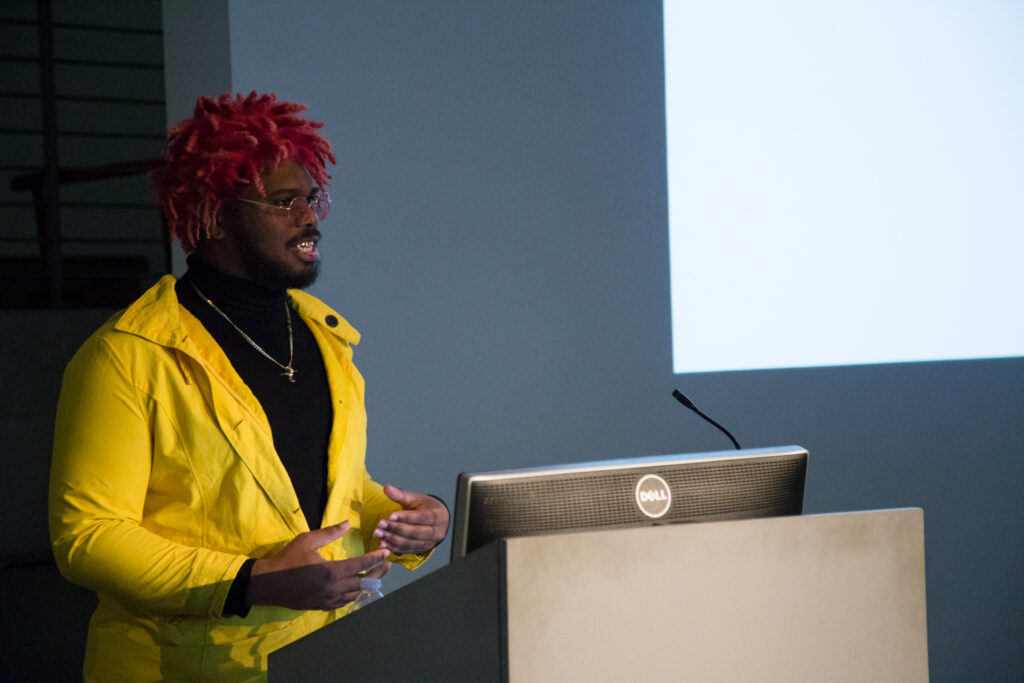 Ka5sh at the EDA pit podium wearing a yellow jacket.