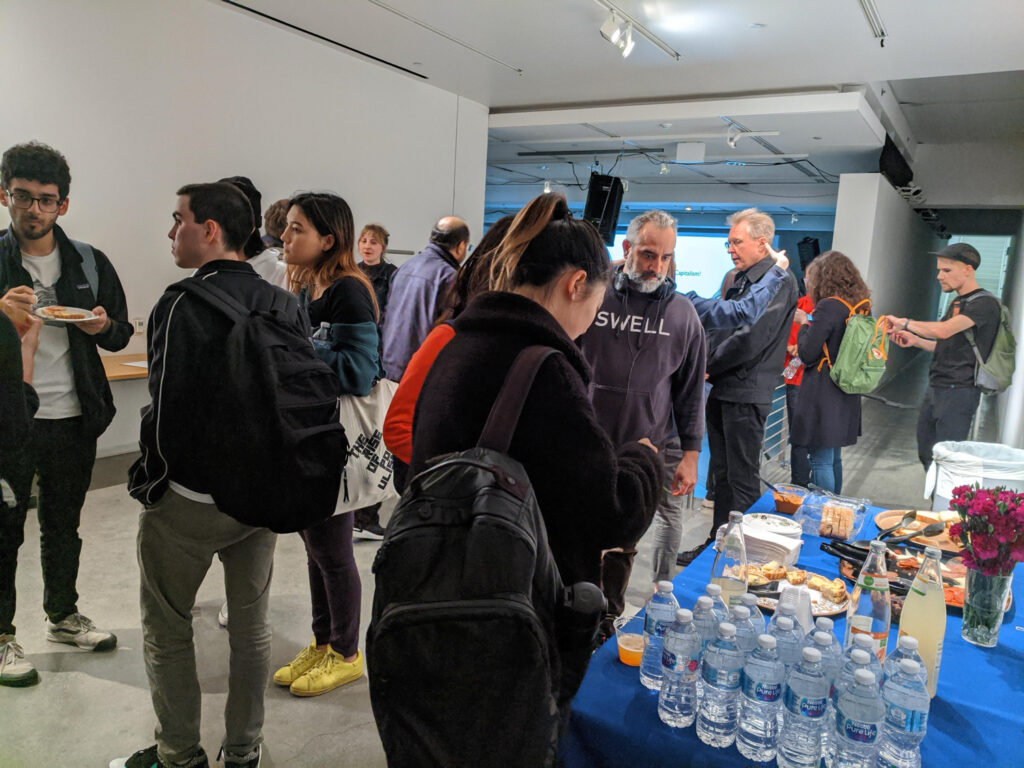 People eating food and socializing at MASAKI FUJIHATA's presentation.