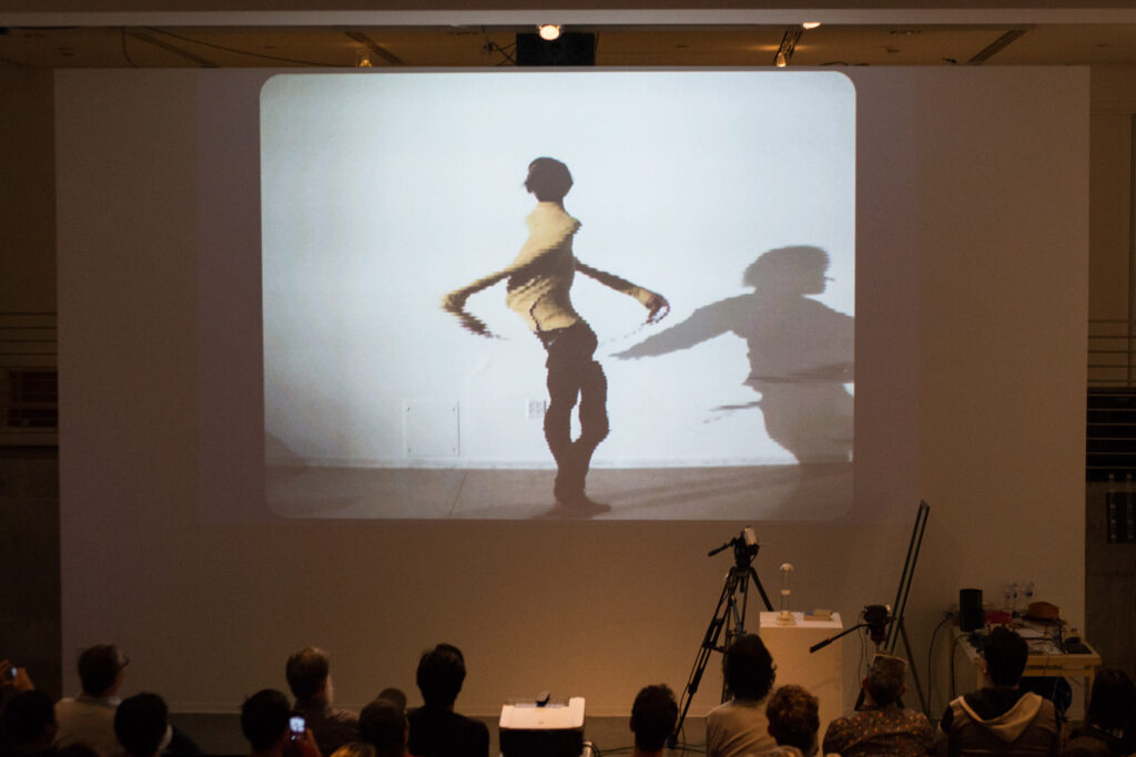 Live slit screening video manipulation of Toshio Iwai in front of a wall.