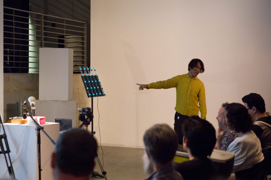 Toshio Iwai is pointing to a sheet music stand.