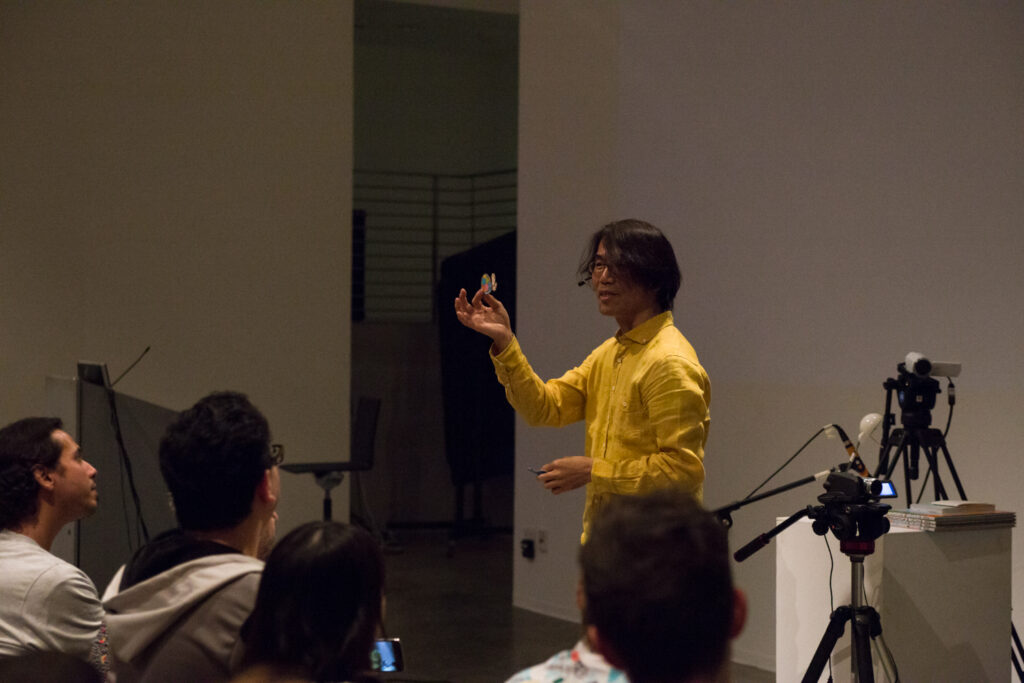 Toshio Iwai holding a small object.