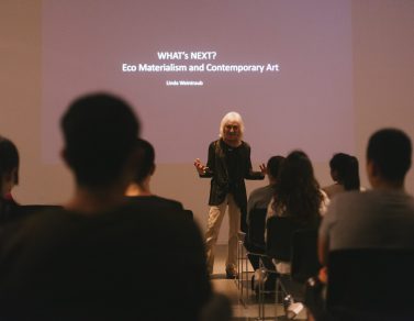 Linda Weintraub standing in front of the crowd, with her hands held out.