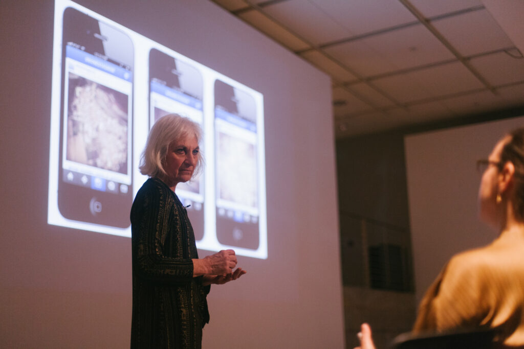 Linda Weintraub is standing in front of her power point slide displaying phones.