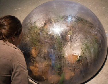 1 person inspecting Maru Garcia's sculpture work on the floor.