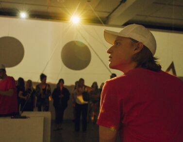 Jack Turpin is wearing a white baseball and pink shirt looking at the projections being displayed on the EDA pit walls.