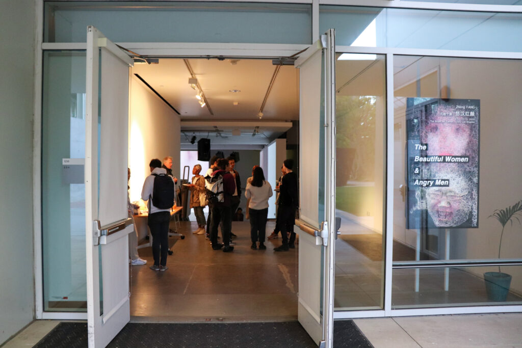 People socializing and eating at the opening of Zheng Fang's exhibition.