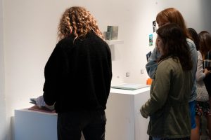 Person wearing gloves and reading a book at the DMA senior show.