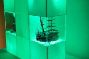 Model of a growing ecosystem inside an acrylic housing. Green leds surround the acrylic housing.
