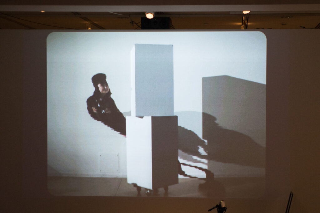 Live slit screening video manipulation of Toshio Iwai in front of a wall.
