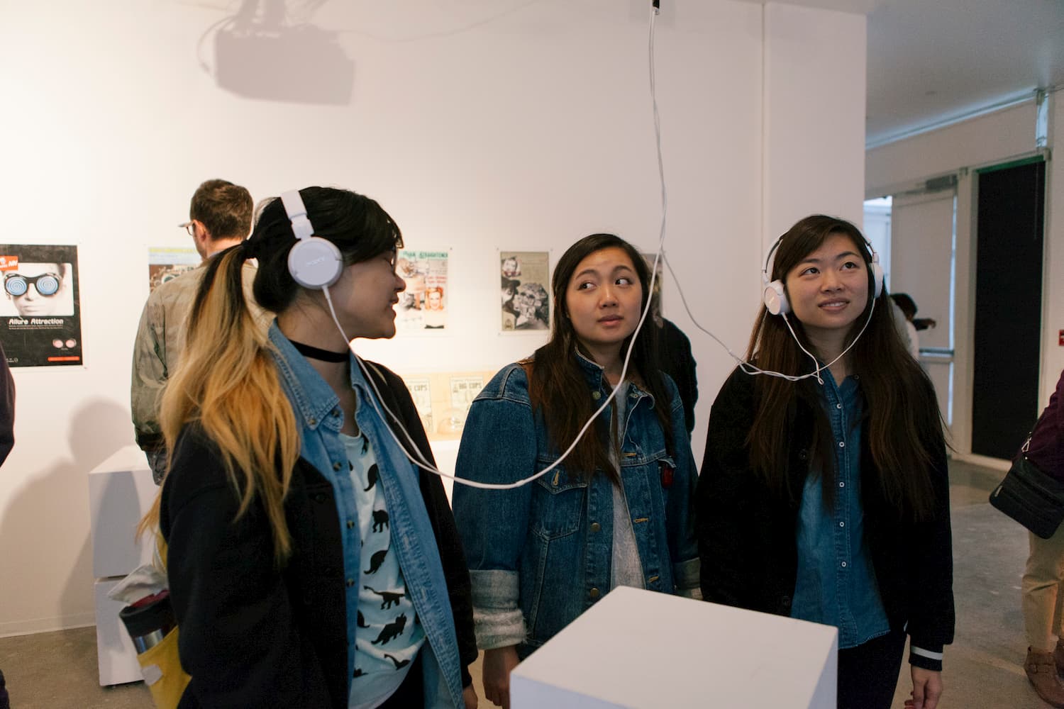 People wearing headphones looking up at a monitor pictured out of frame.