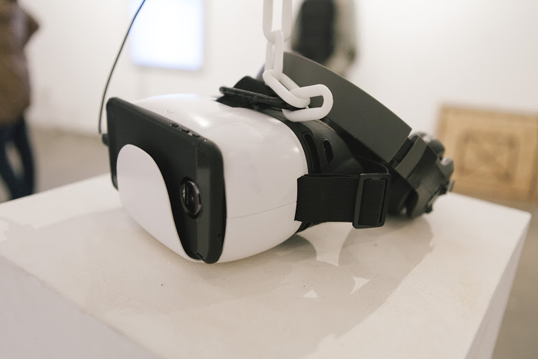 Picture of a VR headset hung by a white plastic chain.