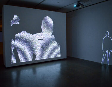 ZEYNEP ABES projection of people on a wall. There is text within the people being projected.
